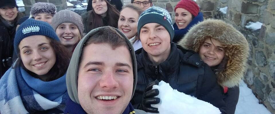 Щасливе селфі, зроблене інтернаціональною групою на вежі . Позаду видніється містою. Один із хлопців тримає в руках снігову брилу.