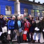 Групове фото учаників проекту на фоні потягу. Всі учасники тримають квитки. На табличці зверху написано: колія №4.