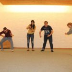 Четверо людей показують сценку на імпровізованій сцені. Кожен учасник репрезентує якусь із ігор: більярд, шахи, настілький футбол, теніс