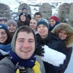 Щасливе селфі, зроблене інтернаціональною групою на вежі . Позаду видніється містою. Один із хлопців тримає в руках снігову брилу.